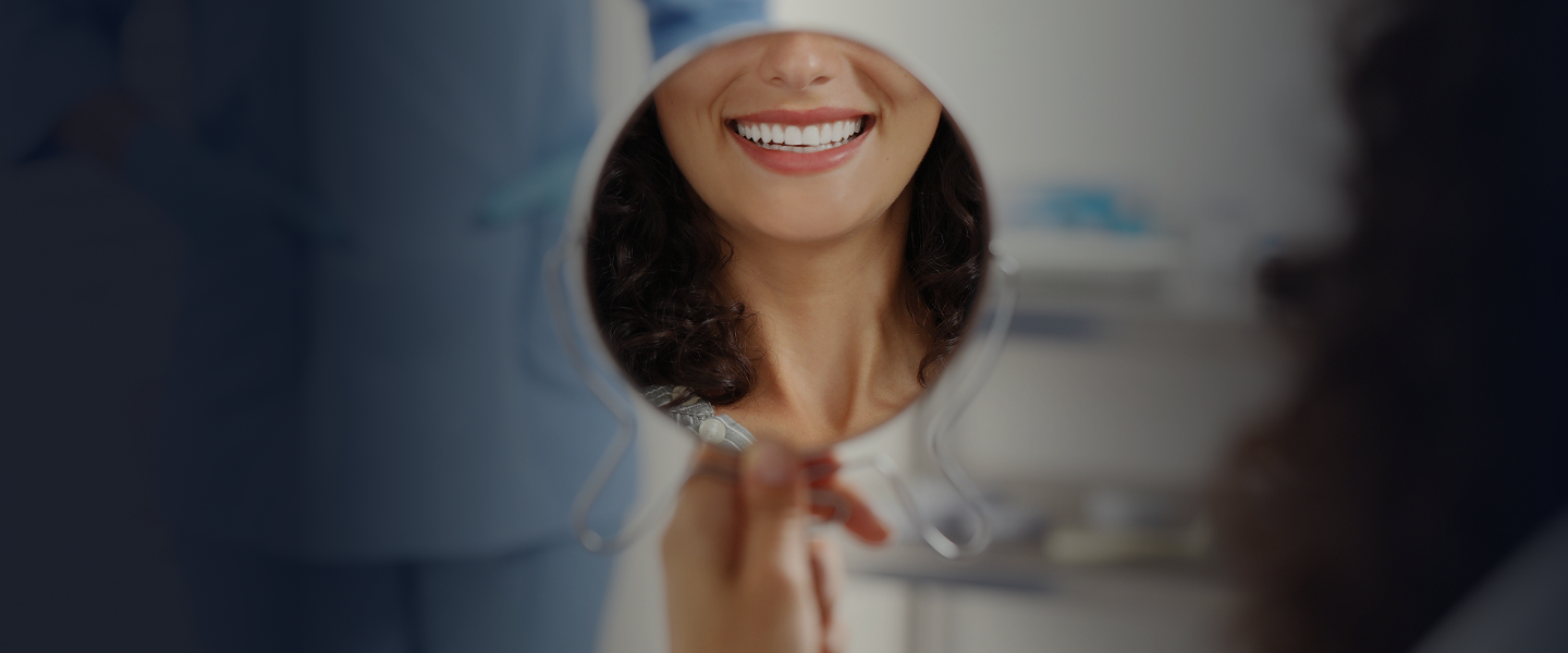 Foto de um espelho de mão refletindo uma boca sorrindo