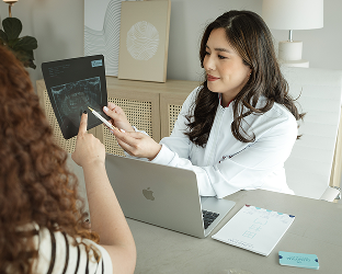Foto da Dra. Mayra apresentando um planejamento com paciente