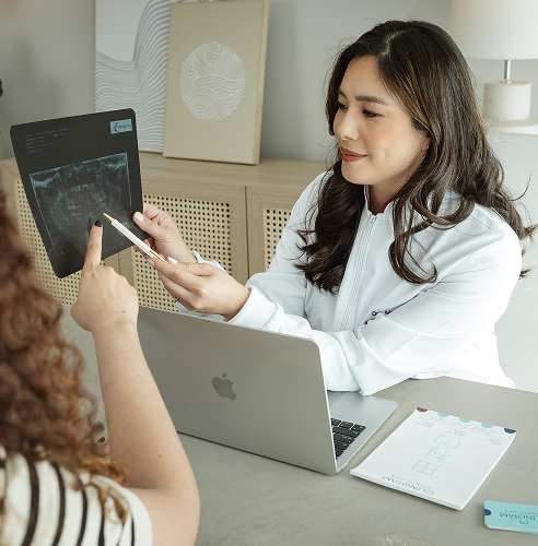 Foto da Dra. Mayra apresentando um planejamento com paciente