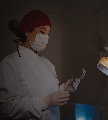 Foto da Dra. Mayra posicionada em frente à cadeira odontológica