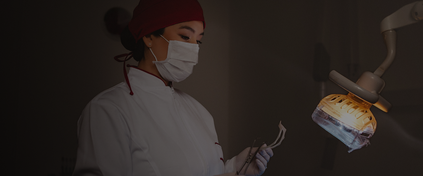 Foto da Dra. Mayra posicionada em frente à cadeira odontológica